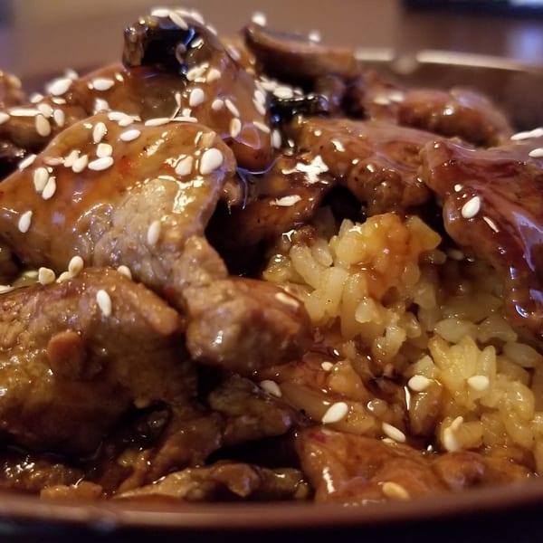 Hibachi Boy's beef and mushroom dish with rice, glazed in sauce and topped with sesame seeds.
